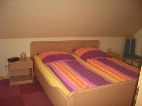 um pequeno quarto com uma cama com lençóis coloridos em Haus Delphin em Neuharlingersiel