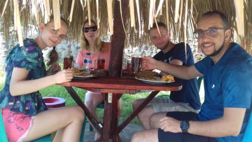 a group of people sitting around a table with food at Mahoni Guest House in Kelimutu