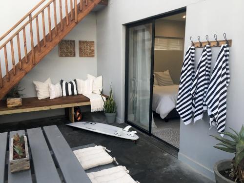 a room with a bed and a surfboard on the floor at Lower Point Surf Studio in Jeffreys Bay