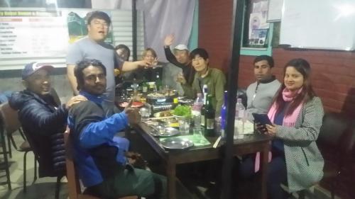 a group of people sitting around a table with food at Harry Guest House & Restaurant in Pokhara