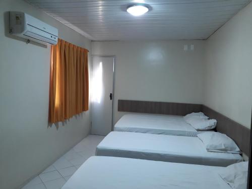 2 camas en una habitación pequeña con ventana en Hotel Pio en Teresina
