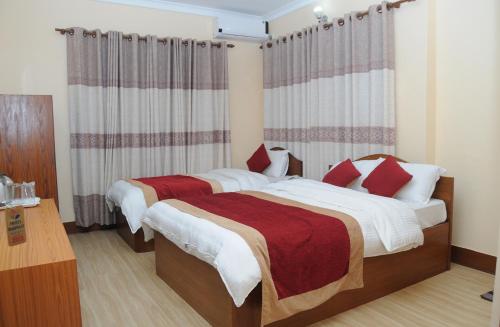 a bedroom with two beds with red and white sheets at Hotel Bagmati in Kathmandu