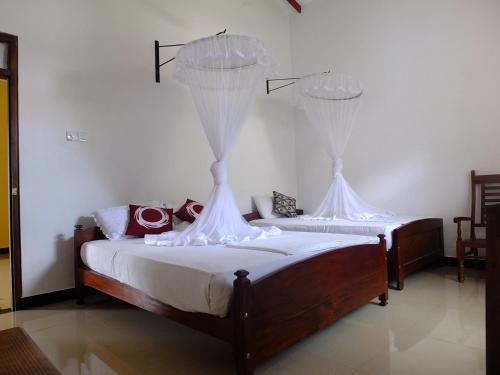 Dos camas en una habitación con paredes blancas. en Freedom Lodge Yala, en Tissamaharama