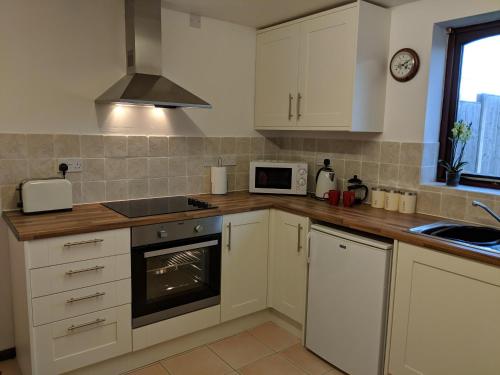 La cuisine est équipée de placards blancs et d'un four avec plaques de cuisson. dans l'établissement Kings Lodge, à Telford