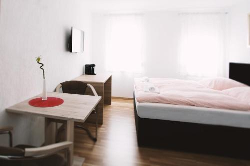 een slaapkamer met een bed en een tafel met een vaas erop bij Waldheim in Nürtingen