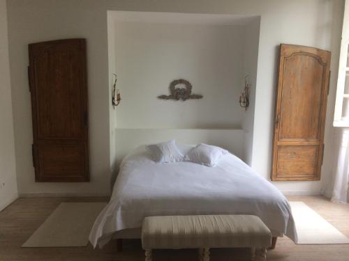 a bedroom with a white bed with a wooden door at L'Ancien Couvent Cahuzac in Cahuzac
