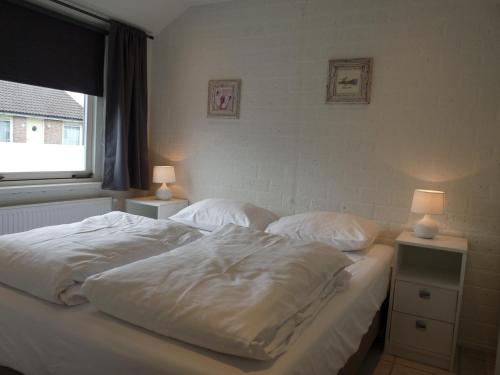 a bedroom with two beds with white sheets and lamps at Buitenhuis Egmond in Egmond aan den Hoef