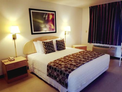 EloyにあるAmericas Best Value Inn-Eloy Casa Grandeの大型ベッド1台とランプ2つが備わるホテルルームです。