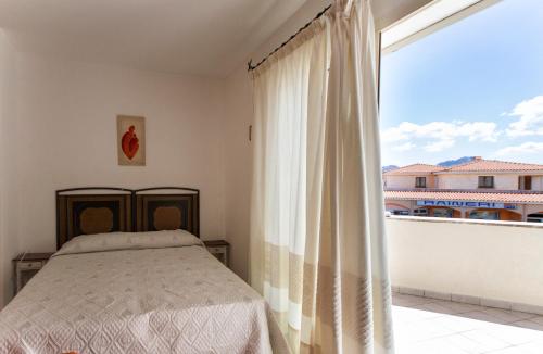 ein Schlafzimmer mit einem Bett und einem großen Fenster in der Unterkunft Appartamento Arzachena Costa Smeralda in Arzachena
