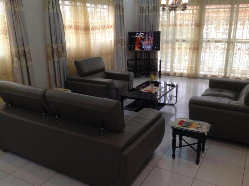 uma sala de estar com um sofá e cadeiras e uma televisão em Bastos'Appart YAOUNDE em Iaundé