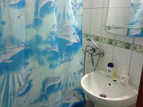 a bathroom with a blue shower curtain and a sink at Soborna Street 259, three-room apartment in Rivne