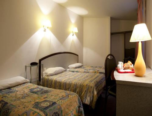 パリにあるホテル ド リューロップのベッド2台、テーブル(ランプ付)が備わる客室です。