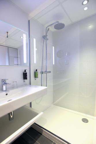 une salle de bain blanche avec une douche et un lavabo dans l'établissement Hôtel Anne De Bretagne, à Rennes