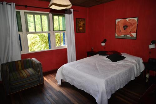 1 dormitorio rojo con 1 cama y 1 silla en Punta Ballena- Rancho Civil- Casa de Campo, Piscina y Playa, en Punta del Este