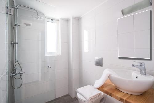 a white bathroom with a sink and a shower at W Suites by Estia in Stalís