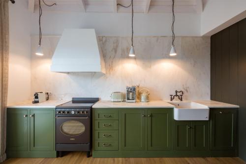 uma cozinha com armários verdes e um lavatório em North Point Houses em Fiskardho