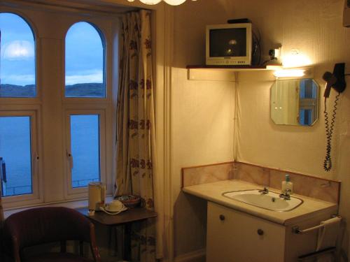 a bathroom with a sink and a tv on the wall at Lancaster Hotel in Oban