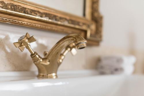 a bathroom sink with a gold faucet in front of a mirror at Alquimista Montevideo in Montevideo