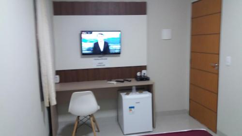 a room with a desk and a tv on the wall at Hijo Buriti Hotel in Mauriti