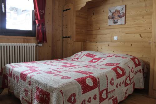 a bedroom with a bed with a red and white blanket at Chalet Fleur des Alpes 1 in Les Gets
