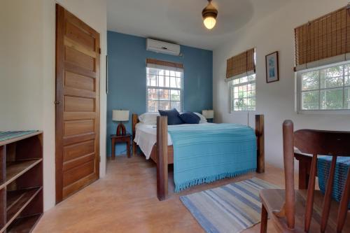 een slaapkamer met een bed met blauwe muren en een deur bij Amanda's Place Casita Carinosa - pool and tropical garden in Caye Caulker