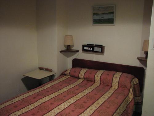 a bedroom with a bed and a table with a lamp at Lancaster Hotel in Oban