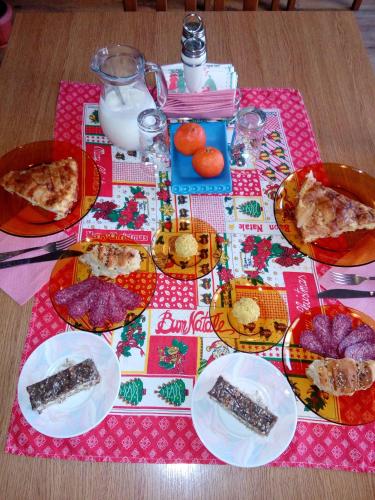 a table with plates of food on a pink table cloth at Guest House Lila in Bansko