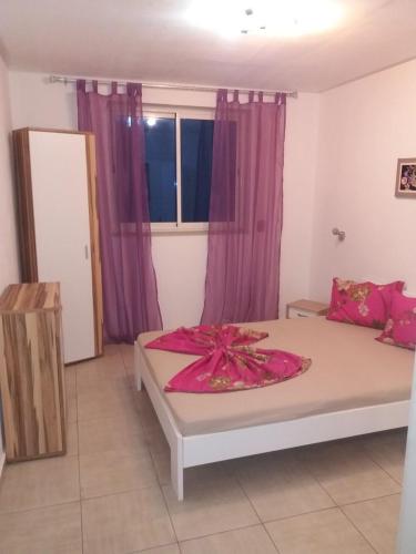 a bedroom with a large bed with purple curtains at Luxus Apartments in Kelibia