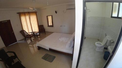 a bedroom with a bed and a toilet in a room at Dolphin Cottage Mirissa in Mirissa