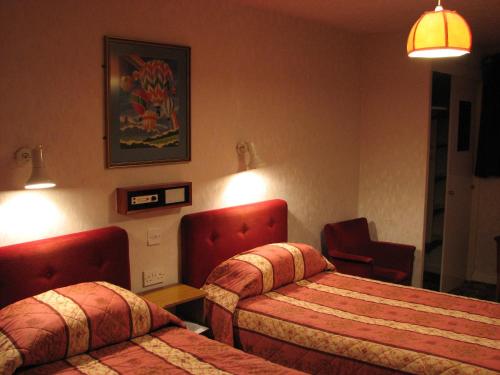 a hotel room with two beds and a chair at Lancaster Hotel in Oban