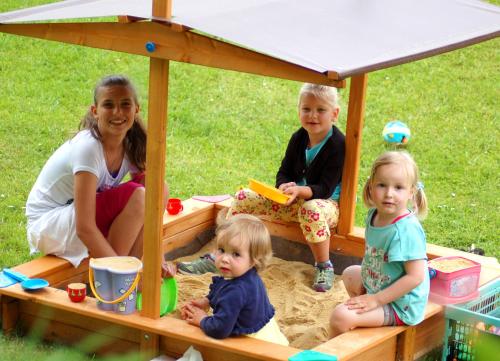 a woman and three children playing in a sandbox at Hinterjetzbachhof in Maria Alm am Steinernen Meer