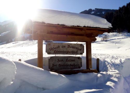 a sign in the snow with the sun behind it at Hinterjetzbachhof in Maria Alm am Steinernen Meer