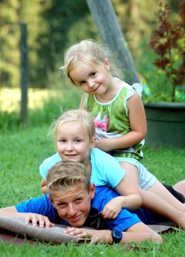 two little girls and a boy laying on the grass at Hinterjetzbachhof in Maria Alm am Steinernen Meer