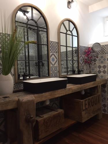 a bathroom with two sinks and two mirrors at Le Nessmann in Sarlat-la-Canéda