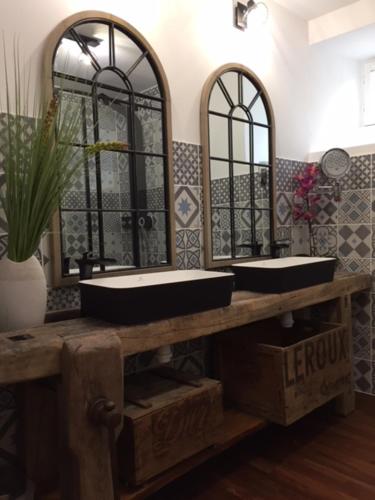 une salle de bain avec deux lavabos et deux miroirs dans l'établissement Le Nessmann, à Sarlat-la-Canéda
