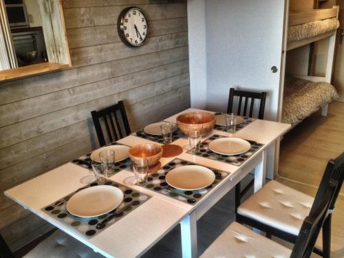 une table avec des assiettes et des bols et une horloge sur un mur dans l'établissement Superbe appart 4/5p balcon plein sud, vue exceptionnelle, retour ski aux pieds, à L'Alpe-d'Huez
