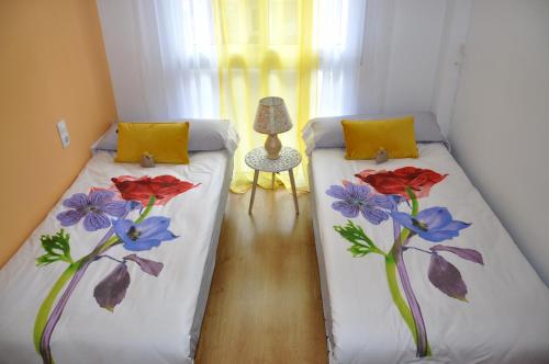 two beds with flowers on them in a room at Agustina Apartment in Alicante