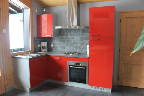 a kitchen with red cabinets and a red refrigerator at Chalet Fleur des Alpes in Les Gets