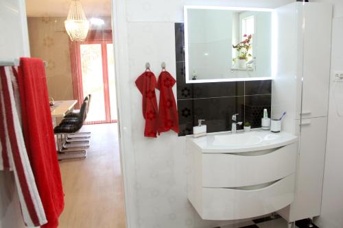 bagno bianco con lavandino e specchio di Apartmani Corleone a Bilice (Bilizze)