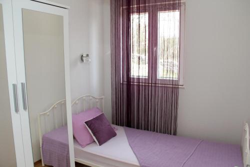 um pequeno quarto com uma cama e uma janela em Apartmani Corleone em Bilice