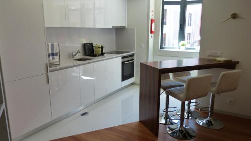kuchnia z białymi szafkami i drewnianym stołem w obiekcie Lux Bolhão - ALL INCLUDED w Porto