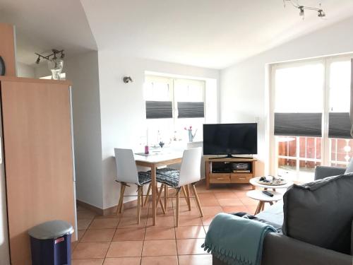 a living room with a table with chairs and a television at Haus Hugo in Zingst