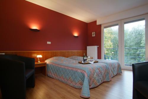 sypialnia z łóżkiem i dużym oknem w obiekcie Hotel Belvedere w mieście Heuvelland