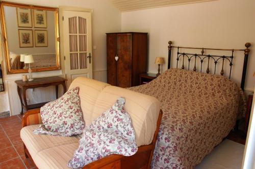 een slaapkamer met een bed en een bank met kussens bij Le Logis du Pressoir Chambre d'Hotes Bed & Breakfast in beautiful 18th Century Estate in the heart of the Loire Valley with heated pool and extensive grounds in Brion