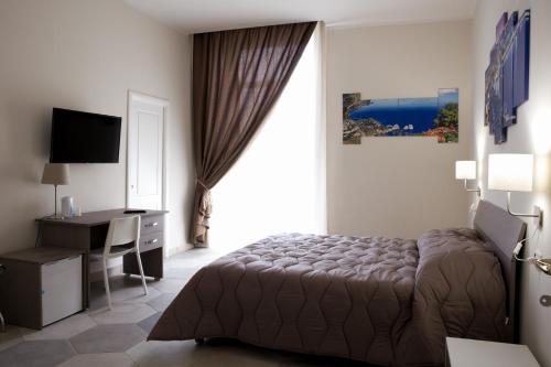 een slaapkamer met een bed, een bureau en een raam bij B&B LA DIMORA DEL CONTE in Napels