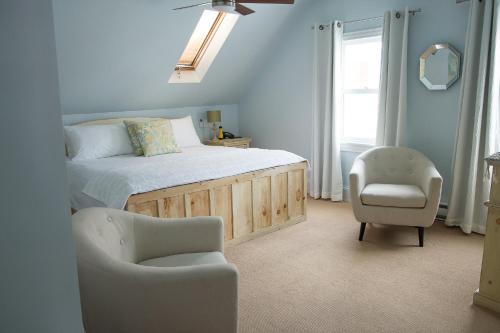 a bedroom with a bed and a chair at Salt Shaker Deli & Inn in Lunenburg