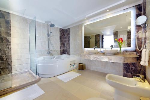 ein Badezimmer mit zwei Waschbecken und einer Badewanne und einem Spiegel in der Unterkunft Sea Beach Edge By Rotana in Sharm El Sheikh