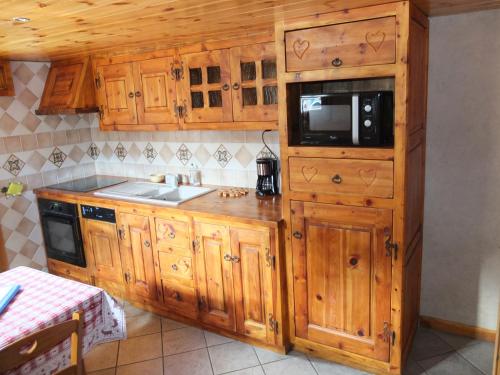 kuchnia z drewnianymi szafkami i kuchenką mikrofalową w obiekcie L'ancolie w mieście Briançon