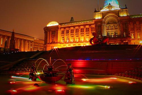 a large building with a fountain in front of it at night at Latitude Chinatown Central Apartment in Birmingham