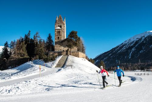 two people cross country skiing in front of a church at Hotel Rosatsch in Pontresina